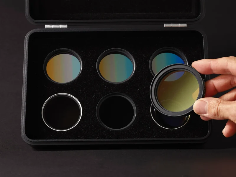 Runde Glasfilter im schwarzen Etui, ein Filter gegen das Licht gehalten